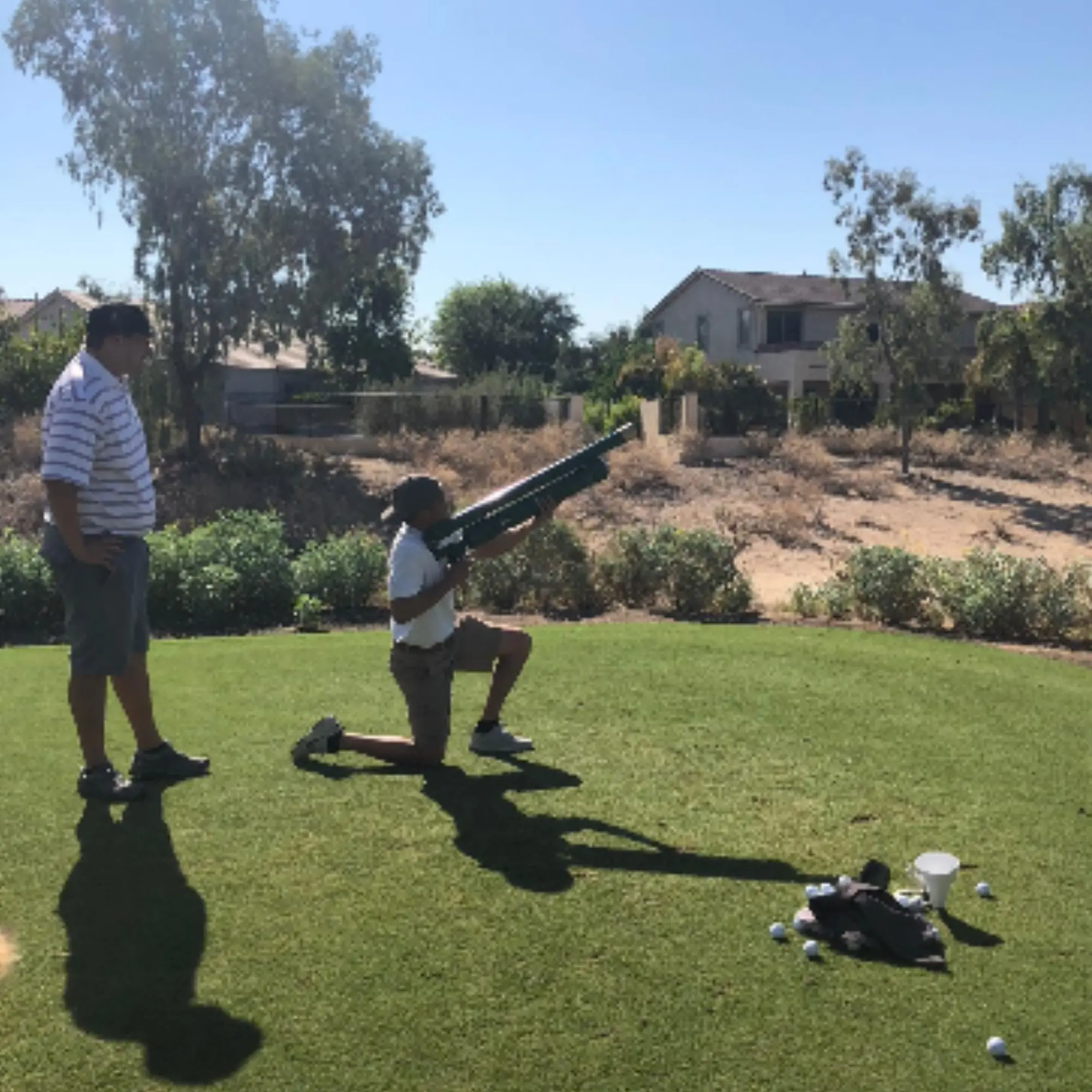 Coach kneeling beside golf equipment on the practice tee