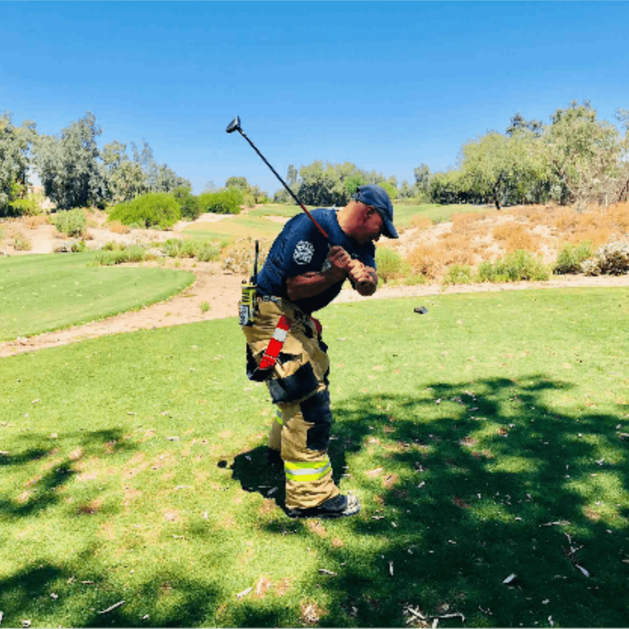 Firefighter in full turnout gear taking a swing on the course