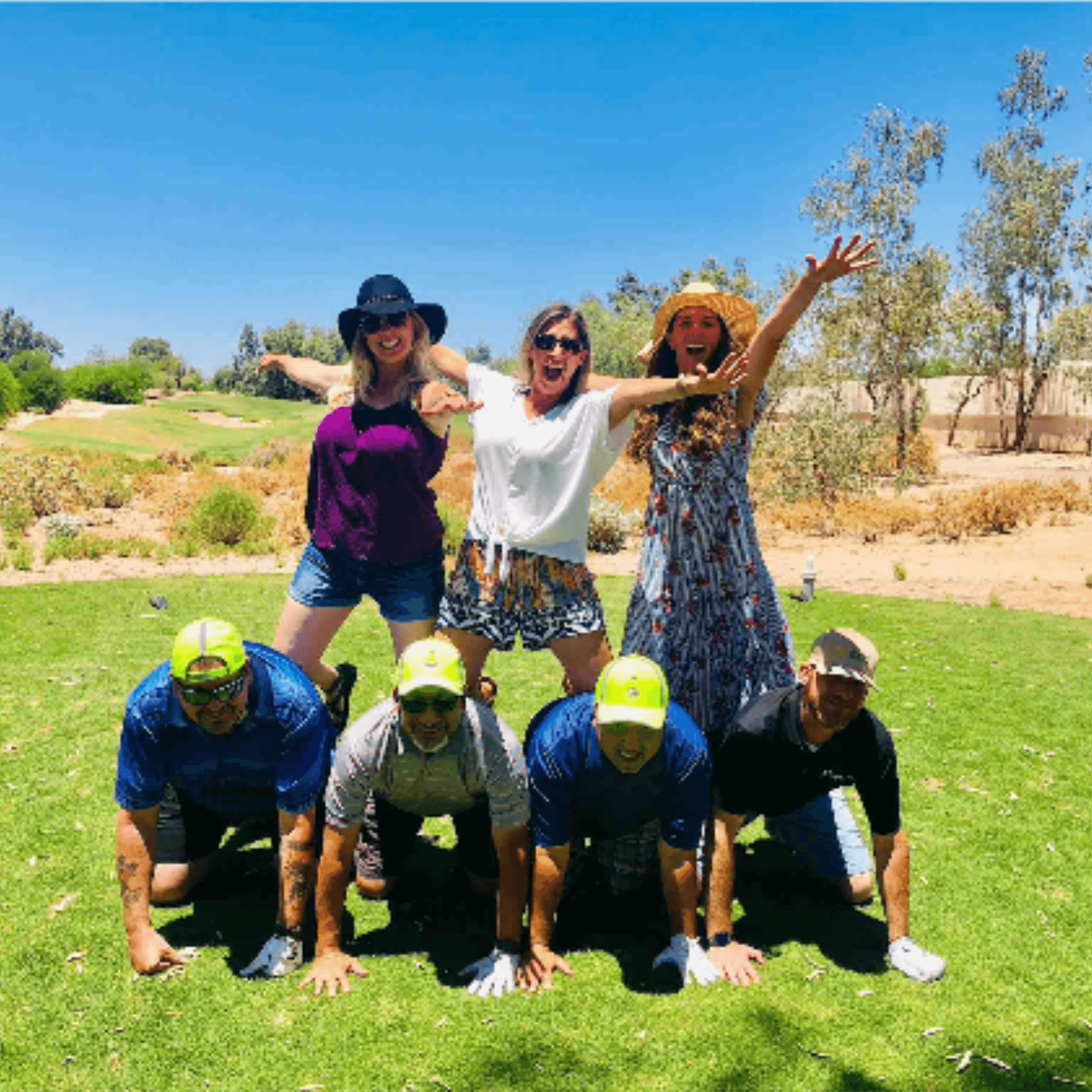 Tournament participants posing in a playful pyramid formation on the green