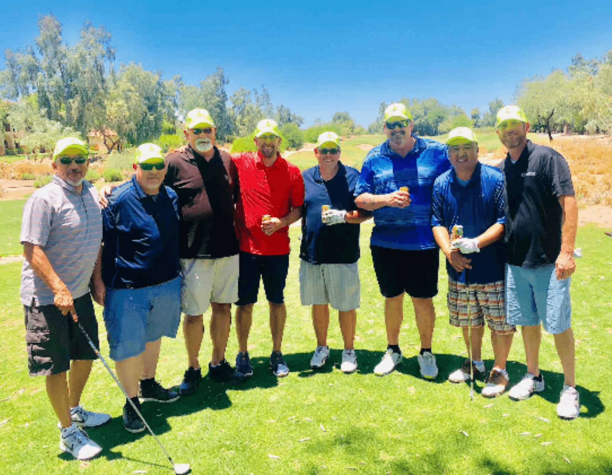 Eight tournament participants in matching white caps posed together on the course